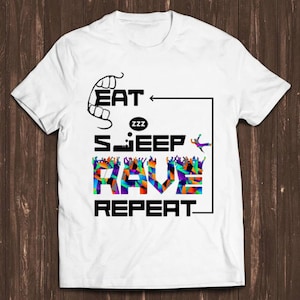 Puede incluir: Camiseta blanca con texto negro que dice "Eat Sleep Rave Repeat" con un gráfico colorido de una multitud de personas en el medio del texto.