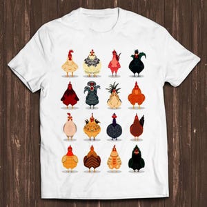 Puede incluir: Una camiseta blanca de manga corta con un estampado gráfico de dieciséis pollos diferentes dispuestos en una cuadrícula de cuatro por cuatro. Cada pollo está ilustrado con un patrón de color distinto, incluyendo tonos de rojo, negro, marrón, blanco y amarillo.