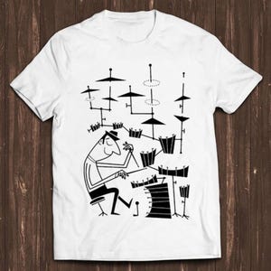 May include: A white short-sleeved t-shirt featuring a black graphic illustration of a stylised drummer sitting at a large drum kit. The design depicts a person playing various drums and cymbals with thin lines and geometric shapes on the front.