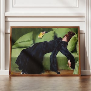 以下が含まれることがあります： 緑色のソファに横たわる女性を描いた絵画。女性は黒いドレスを着て、黄色の本を持っています。女性は黒髪で、横を向いています。