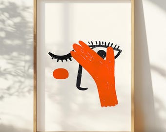 May include: A framed print of a stylised illustration of a face with a hand covering one eye. The eye is black with a white pupil and eyelashes. The hand is orange and the background is white.