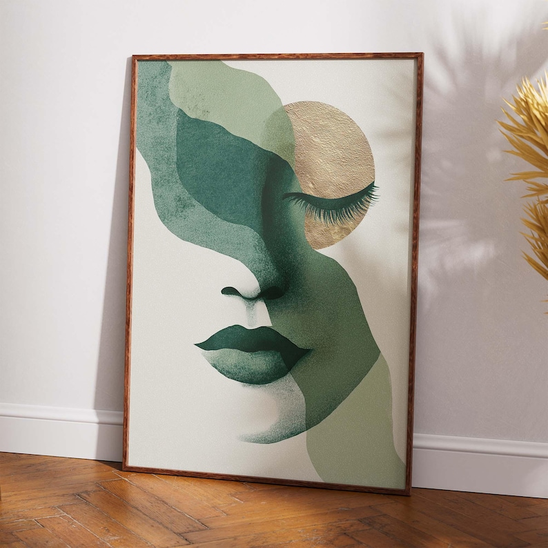 May include: Abstract art print featuring a woman's face in shades of green and gold. The artwork has a minimalist style with a closed eye, full lips, and a gold circle. The print is framed in a brown wooden frame.