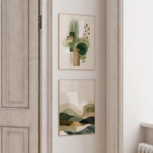 May include: Two framed abstract art prints. The top print features green brushstrokes, geometric shapes, and a sprig of leaves. The bottom print depicts a landscape with rolling hills in shades of green, brown, and beige. Both prints have gold frames.