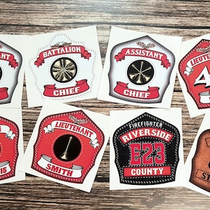May include: Eight different firefighter helmet decals with various titles and names. The decals are printed on white paper with red, black, and brown accents. The decals feature text such as "Assistant Chief", "Battalion Chief", "Captain", "Lieutenant", "Engine 36", "Firefighter Riverside E23 County", and "Lieutenant 45 Smith".