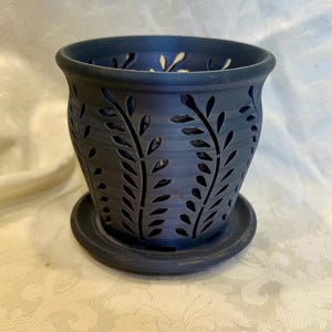 May include: A dark gray ceramic planter with a decorative leaf pattern. The planter has a matching saucer.
