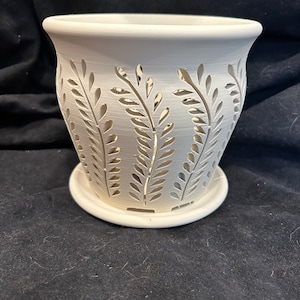 May include: White ceramic planter with a decorative leaf pattern. The planter has a removable base.