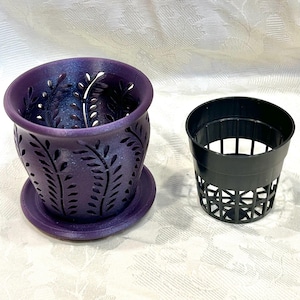 May include: A purple, glittery, cylindrical planter with a cutout leaf pattern and a matching circular base tray, positioned next to a separate, black, plastic, slotted net pot insert designed for drainage and airflow in plant cultivation.