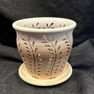 May include: A white ceramic planter with a brown ombre design and a cutout pattern of leaves. The planter has a matching saucer.