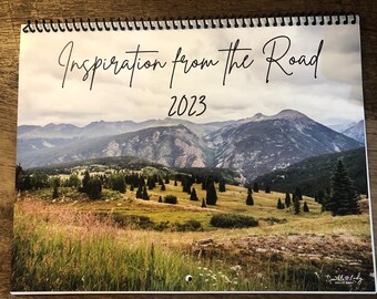 May include: A 2023 calendar with a mountain range landscape photo. The text "Inspiration from the Road" is at the top of the calendar.