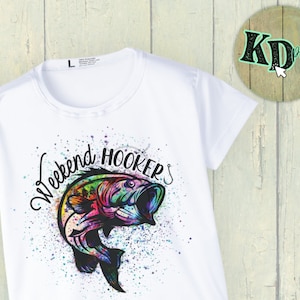 May include: White t-shirt featuring a colourful graphic of a fish leaping out of the water with the text "Weekend Hooker's" above it.