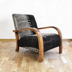 May include: An armchair with a black and white patterned fabric seat and back. The chair has curved wooden armrests and legs. The design is a mix of modern and vintage styles, suitable for a living room or reading nook.