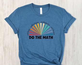 May include: Blue t-shirt with rolled sleeves and a knotted hem. The shirt features a colourful graphic of a sunburst design with the words "DO THE MATH" in bold black letters. Above the sunburst are the words "add hope, subtract fear, multiply love, end division."
