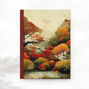 May include: A personalized journal with a red cover and a watercolor illustration of a forest scene with trees in shades of red, orange, yellow, and green. The text "ANDREA" is printed on the cover.