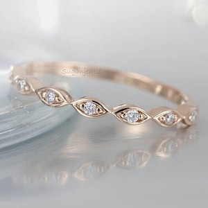 May include: A delicate rose gold band with a row of small, round diamonds set in a scalloped design.