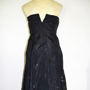 May include: A black strapless gown with a silver floral pattern. The gown has a fitted bodice and a flowing skirt.