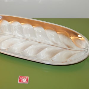 May include: A silver serving tray shaped like a leaf with a handle. The tray has a raised design of veins on the leaf.