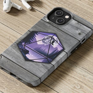 Puede incluir: Una funda para teléfono con un diseño de veta de madera que presenta una forma geométrica púrpura y negra con una escena de luna y bosque en su interior.