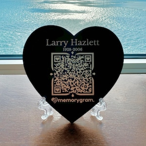May include: Black heart-shaped plaque with a QR code and the text "Larry Hazlett 1928-2006" and the logo "memorygram."
