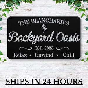 May include: Black metal sign with silver text that reads "The Blanchard's Backyard Oasis Est. 2023 Relax Unwind Chill". The sign features a palm tree graphic.