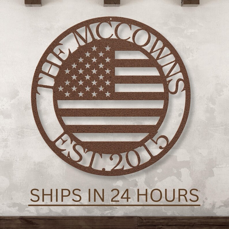 May include: A circular, brown metal sign featuring the American flag design. The family name "The McCowns" is arched around the top, with "EST 2015" at the bottom. The sign is mounted on a textured wall.