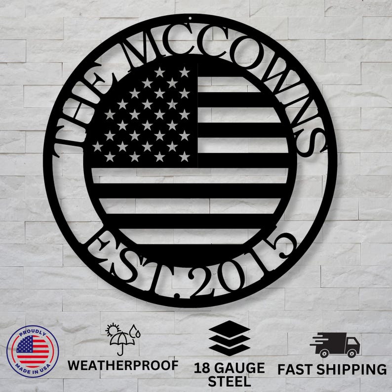 May include: Black metal wall art featuring the American flag design with the text "THE MCCOWNS EST. 2015" in a circular frame. The flag has white stars and black and white stripes. The art is made of 18 gauge steel.