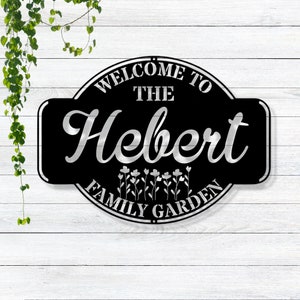 May include: Black metal sign with white lettering that reads "Welcome to the Hebert Family Garden".