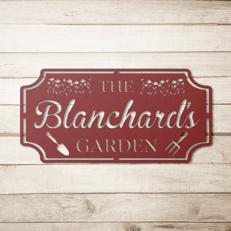 K&ouml;nnte beinhalten: Rotes Metall-Gartenschild mit dem Text "The Blanchard's Garden" mit einem Design aus Schaufel und Gabel.