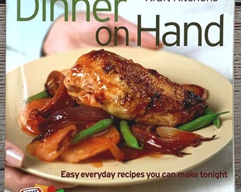 Puede incluir: Un libro de cocina titulado "Dinner on Hand" de Kraft Kitchens. La portada presenta un plato de comida cocinada, que incluye un trozo de carne, verduras y judías verdes. También es visible el texto "Easy everyday recipes you can make tonight".