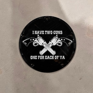 May include: Black round motorcycle cover with white text that reads "I have two guns, one for each of ya" and a graphic of two crossed pistols.
