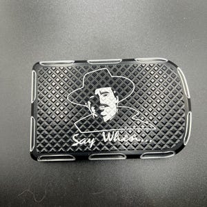 May include: Black rectangular metal plate with a diamond pattern and a white outline. The plate features a white graphic of a cowboy and the text "Say When..."