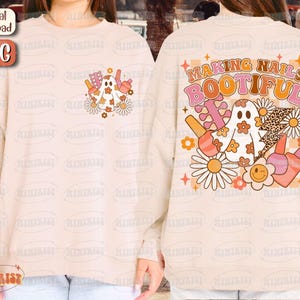 May include: A cream-colored sweatshirt with a graphic design featuring a ghost, daisies, nail polish bottles, and the text "MAKING NAILS BOOTIFUL." The design has a retro, groovy aesthetic with orange, pink, and brown colors.