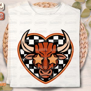 May include: A white t-shirt with a red and black checkered heart design featuring a bull with star-shaped sunglasses.