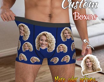 May include: Navy blue boxer shorts with a repeating pattern of a woman's face. The text "Custom Boxers" is displayed in white script. The phrase "More color options..." is also visible.