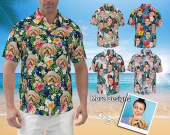 Puede incluir: Un hombre lleva una camisa hawaiana azul y blanca con un patrón de perros y flores. La camisa tiene un cuello abotonado y mangas cortas. El hombre está de pie frente a una escena de playa. El texto "More Designs" es visible en la imagen.