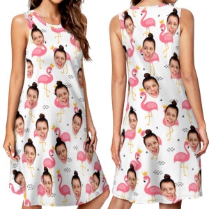 May include: A white sleeveless dress with a pattern of pink flamingos with a person's face on each flamingo's head. The dress has a loose fit and a slightly flared skirt.
