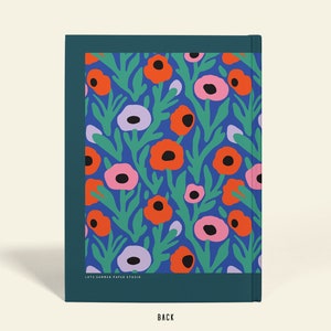 May include: A notebook with a floral design. The cover displays orange, pink, and purple flowers with green leaves on a blue backdrop. The notebook has a dark teal border and the word "BACK" at the bottom.