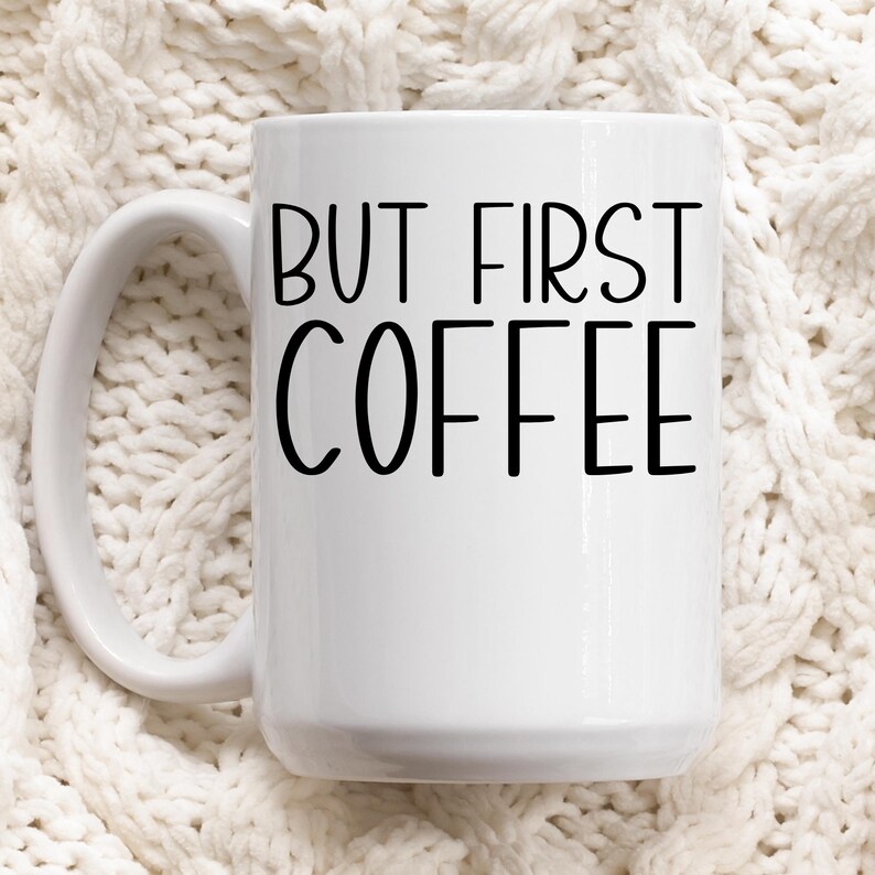 Puede incluir: Taza de caf&eacute; de cer&aacute;mica blanca con texto negro que dice "But First Coffee".