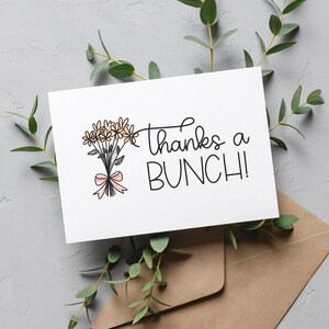 Puede incluir: Una tarjeta blanca con un ramo de flores amarillas dibujado a mano con una cinta rosa y el texto "Thanks a BUNCH!" en cursiva negra.