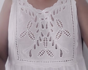 May include: White sleeveless top with a delicate lace pattern around the neckline. The lace features a floral design with small, intricate details.