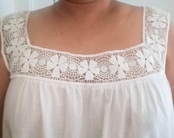 Peut inclure: Top blanc sans manches avec un décolleté carré et une délicate bordure en dentelle ornée de motifs floraux.
