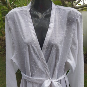 May include: White cotton robe with a long sleeve, a V-neck, and a tie belt.