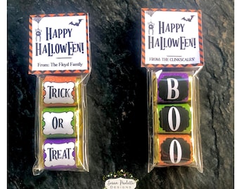 May include: Two cellophane bags filled with Halloween-themed chocolate candy bars. The bags are decorated with orange and black striped paper and a white tag with the text "Happy Halloween!" and a message from the giver. One bag has the words "Trick or Treat" on the candy bars, and the other bag has the word "BOO" on the candy bars.