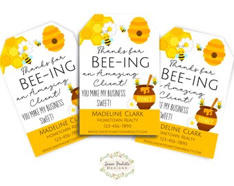 Peut inclure: Trois étiquettes cadeaux jaunes et noires sur le thème des abeilles avec le texte "Merci d'être un client extraordinaire ! Vous rendez mon entreprise douce !" et un pot de miel avec une abeille sur le dessus. Les étiquettes comprennent également le nom "Madeline Clark" et les coordonnées de Hometown Realty.