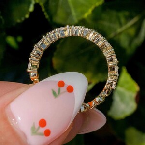 May include: A gold band ring with a row of small, clear stones set in a pave setting.