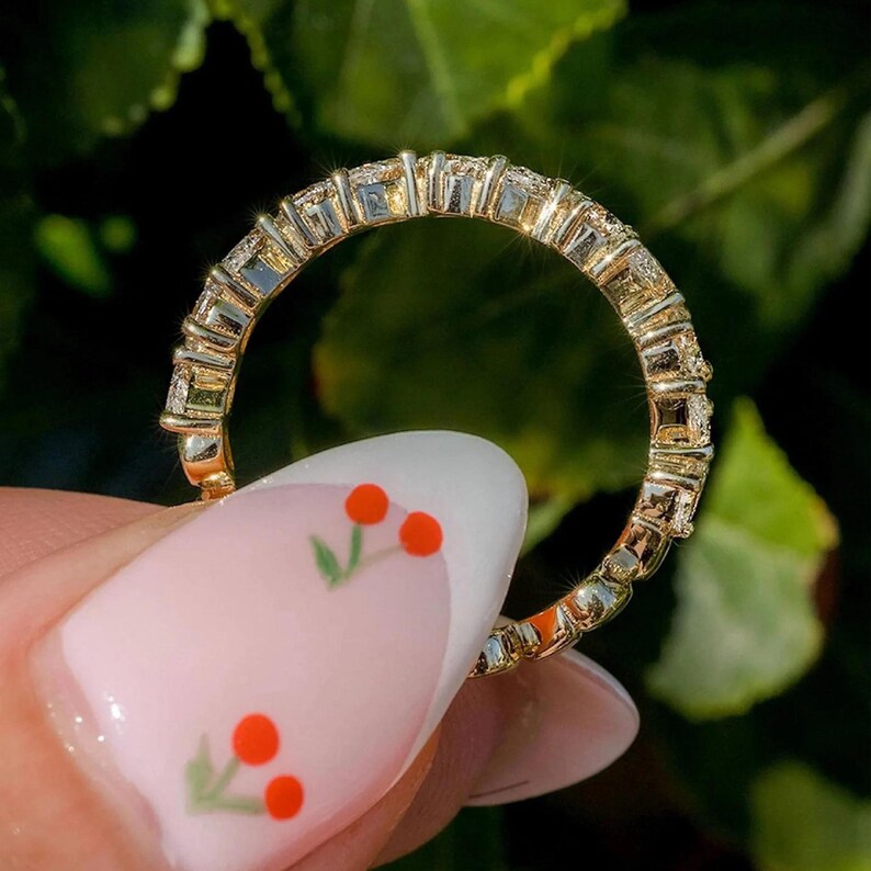 May include: A gold band ring with a row of small, clear stones set in a pave setting.