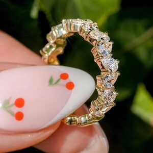 May include: A gold band ring with a row of pear-shaped diamonds set in a prong setting.