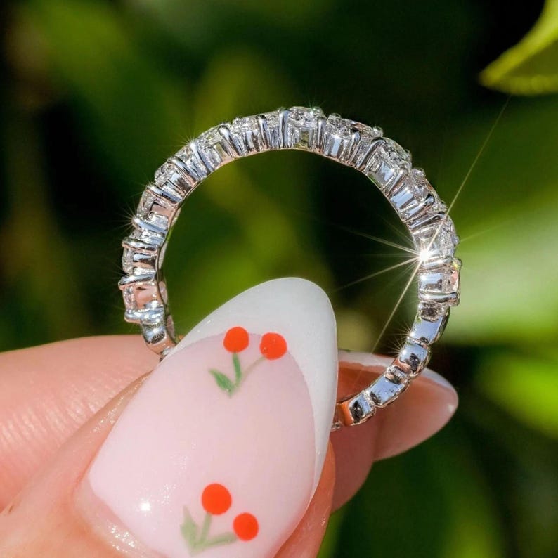 May include: A silver band ring with a row of small, clear diamonds set in a pave setting.