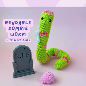 May include: A green and pink crocheted zombie worm with black eyes and a bone accessory. The worm is bendable and comes with a gray tombstone that says "R.I.P." and a pink brain.