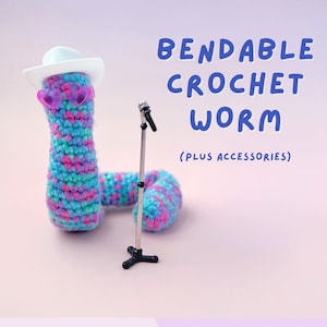 May include: A bendable crochet worm in shades of blue, pink, and purple, wearing a white hat and heart-shaped sunglasses. A miniature microphone stand is next to the worm. Text reads "BENDABLE CROCHET WORM (PLUS ACCESSORIES)".