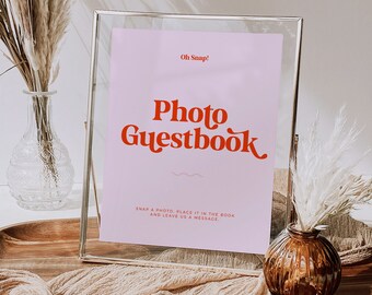 May include: A silver frame with a pink background and the text "Oh Snap! Photo Guestbook" in red. The text below reads "Snap a photo, place it in the book and leave us a message."